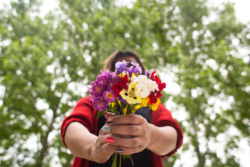 A woman holding colorful flowers in an outdoor setting